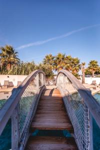 a wooden bridge over a body of water with palm trees at Le Phare in Les Portes