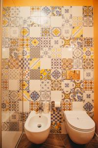 a bathroom with a toilet and a tiled wall at Venti D'Amare Suites in Polignano a Mare