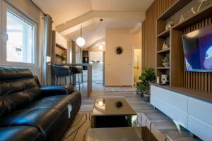 een woonkamer met een leren bank en een tv bij Apartmani Tip-Top in Tivat