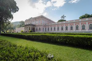 a large pink building with a hedge in front of it at Casa com Wi-Fi e garagem a 400m do Museu Imperial in Petrópolis
