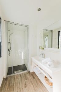 a white bathroom with a shower and a sink at Le Phare in Les Portes