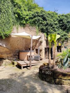 a patio with a table and an umbrella at Evasion Troglodyte insolite spa et nature in Doué-la-Fontaine