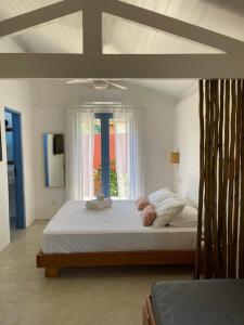 a bedroom with a large white bed with a window at Villa Tennis in Ubatuba