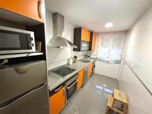 a kitchen with orange and white cabinets and a microwave at Apartamento Playa Foz in Foz +8 photos