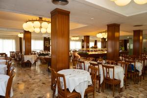 a restaurant with white tables and chairs and a bar at Hotel Haromar in Calella