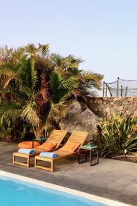 two lounge chairs sitting next to a swimming pool at Golden Wave Villa Lajares in Lajares