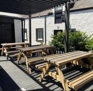 three wooden picnic tables sitting on a deck at Kings Arms Hotel in Melrose