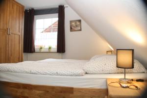 a bedroom with a bed and a window at Ferienhaus Maren in Nessmersiel an der Nordsee - hochwertig und gemütlich in Dornum
