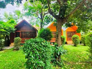 an orange house with a tree in the yard at สวนไมตรีจิต รีสอร์ท in Ban Khlong Si