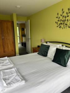 a bedroom with a large white bed with green walls at Bryn Melyn Apartments in Barmouth