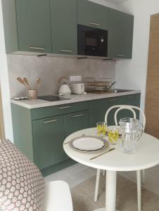 una cocina con armarios verdes y una mesa y sillas blancas. en Studio dans Maison Familiale, en Locoal-Mendon