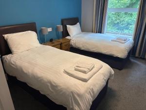 a room with two beds with white sheets and a window at Bryn Melyn Apartments in Barmouth