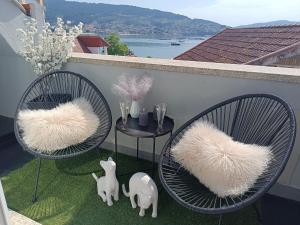 two chairs with white cushions sitting on a balcony at Rincón del Mar Terrazas y vistas a la Ría de Vigo in Moaña