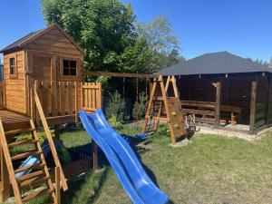 a playground with a slide and a wooden house at Krasnobród Dom Całoroczny in Krasnobród