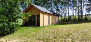 a small wooden building on a grassy field at Domek nad jeziorem Giżyno - cisza i natura Piotiwo D3 in Giżyno