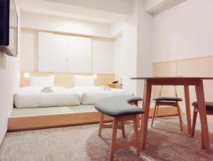 1 dormitorio con 1 cama con escritorio y 2 sillas en Apartment Hotel DIG the OSAKA, en Suita