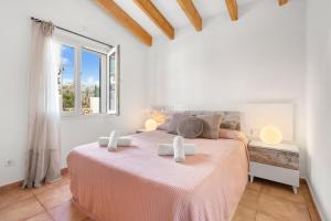 a white bedroom with a pink bed in a room with a window at Villa Vergara in Cala en Porter