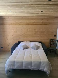 a bedroom with a white bed with a wooden wall at Ma P'tite Étoile in Le Grand-Bornand
