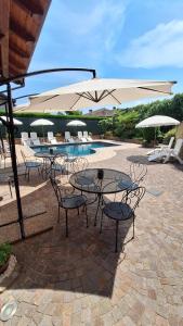 a patio with tables and chairs and an umbrella at Villa Laura B&B in Fossano