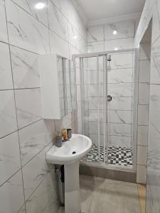 a white bathroom with a sink and a shower at WiseStar Guest House in Johannesburg
