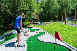 a boy playing golf in a miniature golf course at Sleeps 14 Pool Hot Tub Sauna Pickleball Arcade in Stroudsburg
