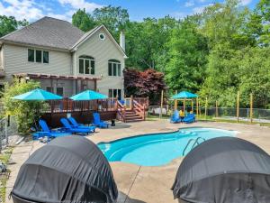 a house with a swimming pool with blue chairs and umbrellas at Sleeps 14 Pool Hot Tub Sauna Pickleball Arcade in Stroudsburg