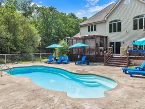 a swimming pool with blue chairs and a house at Sleeps 14 Pool Hot Tub Sauna Pickleball Arcade in Stroudsburg