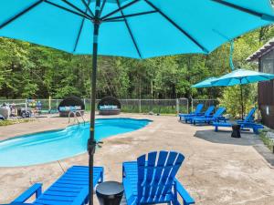 a pool with blue chairs and an umbrella at Sleeps 14 Pool Hot Tub Sauna Pickleball Arcade in Stroudsburg