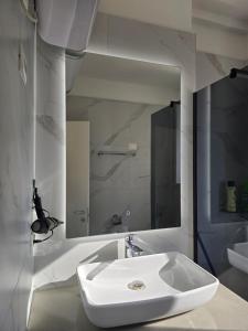 a white bathroom with a sink and a mirror at Olive Breeze Drymades in Dhërmi