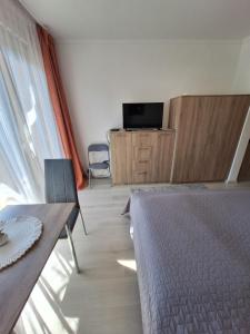 a bedroom with a bed and a tv and a table at Sunrise Apartman in Siófok