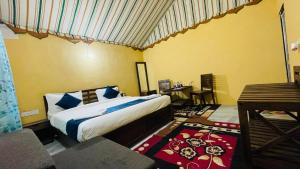 斋沙默尔Shriram Desert Camp Jaisalmer的房间里有一张床和一张书桌的卧室 更多70张照片