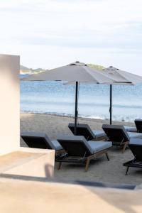 a group of chairs and an umbrella on the beach at Physis Oikos Beachfront Apartments in Skiathos Town