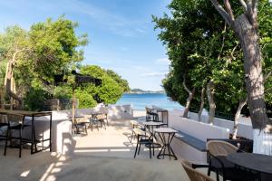 a patio with tables and chairs next to the water at Physis Oikos Beachfront Apartments in Skiathos +14 photos