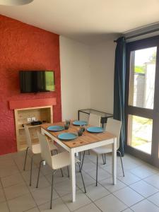 a dining room with a table with chairs and a tv at Joli Gîte Rouge Au Bord Du Lac in Saint-Rémy-sur-Durolle