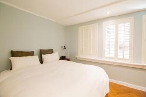 a white bedroom with a large bed and a window at 朵兒dor韓國汗蒸幕 동대문점 商務旅店 in Taipei