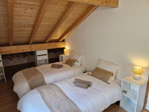 two beds in a room with wooden ceilings at Appartement rénové Au Rain Grébatte avec terrasse in La Croix-aux-Mines
