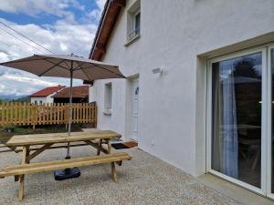 a wooden picnic table with an umbrella on a patio at Appartement rénové Au Rain Grébatte avec terrasse in La Croix-aux-Mines