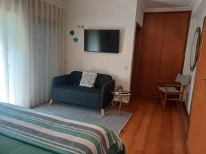 a living room with a blue couch and a tv at Casa da Pedralva in Nazaré