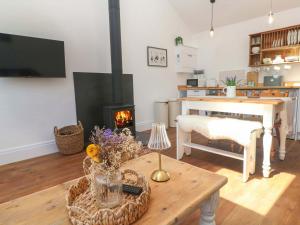 a living room with a table and a fireplace at Lavender Cottage in Helston