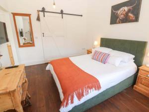 a bedroom with a bed and a desk and a mirror at Lavender Cottage in Helston