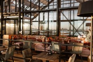 a restaurant with a couch and tables and windows at Hotel Torpedoloods in Hoek van Holland