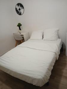 ein weißes Bett mit weißen Laken und eine Pflanze auf einem Tisch in der Unterkunft Chambre à 20 minutes de Paris TOUR EIFFEL, APPARTEMENT COMMUN in Épinay-sur-Seine