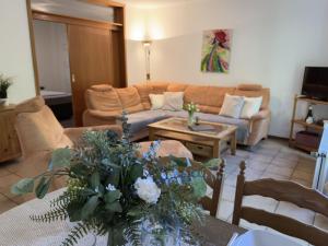 a living room with a couch and a table with flowers at Gästehaus Vogel - Silbermöwe in Horumersiel