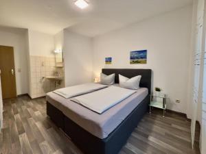 a bedroom with a large bed with white sheets at Gästehaus Vogel - Silbermöwe in Horumersiel