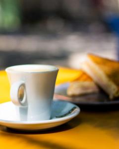 Una taza de café blanco sobre una mesa con un sándwich. en Mini Bell, en Gerez