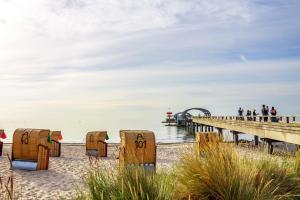 ein Strand mit Stühlen im Sand und einem Pier in der Unterkunft Ferienwohnung Herzmuschel für 5 Gäste mit Sauna und Garten, strandnah in Kellenhusen