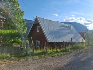a red barn with a metal roof on the side of a road at ROOMSbyVOJKAN in Pljevlja