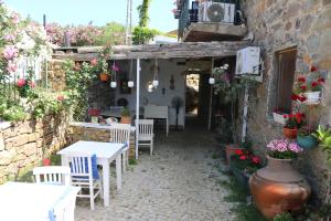 a patio with white tables and chairs and flowers at Son Vapur Otel in Gökçeada