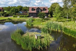 a house with a pond in front of it at The Lakehouse Apartment by inspirestays-com in Rudgwick