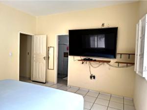 a bedroom with a flat screen tv on the wall at Sol e Praia in Prado